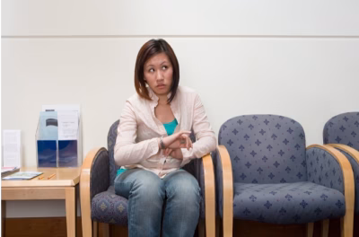 Woman in medical waiting room looking upward with hand raised near her chest