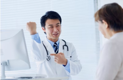 Doctor in white coat with stethoscope showing patient an X-ray image while explaining results in bright medical office