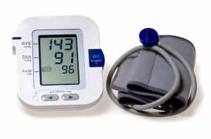 Digital blood pressure monitor displaying 143 over 96 with pulse of 96, shown with inflated arm cuff connected by blue tubes